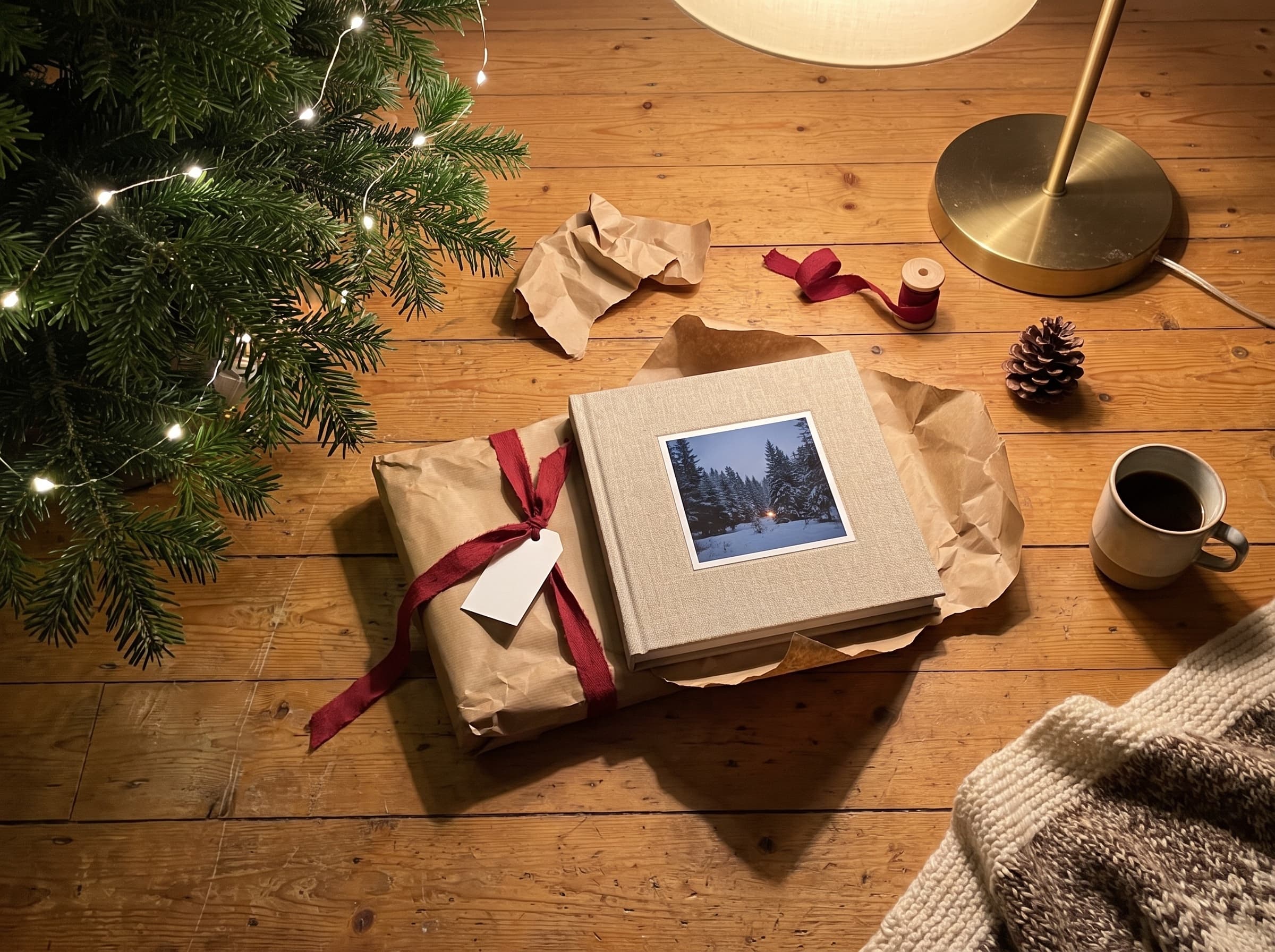 A linen photo book half unwrapped from kraft paper under a Christmas tree